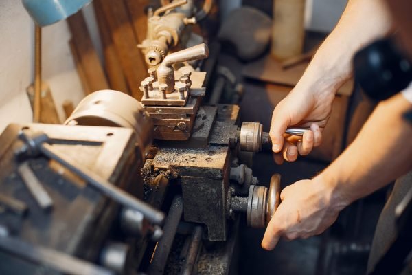 Man working with a wood. Carpenter in a white shirt